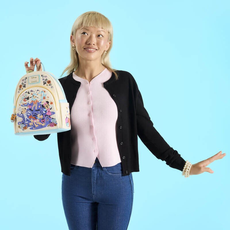Model holding the Loungefly Disney Mickey and Friends Halloween mini backpack against a blue backdrop