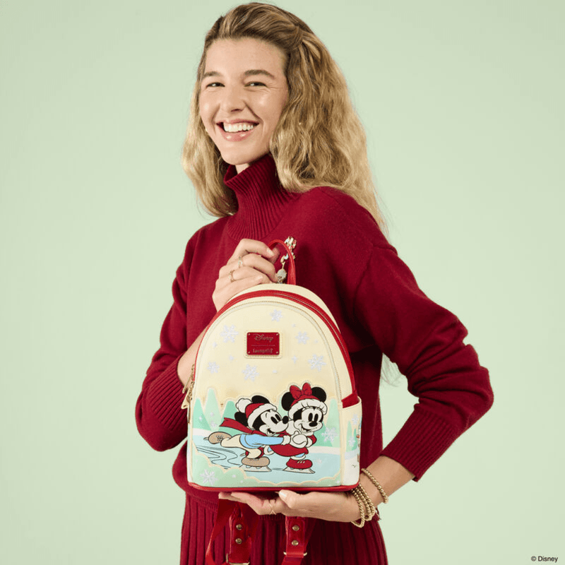 Model holding Loungefly Disney Mickey and Minnie Christmas Ice Skating Mini Backpack