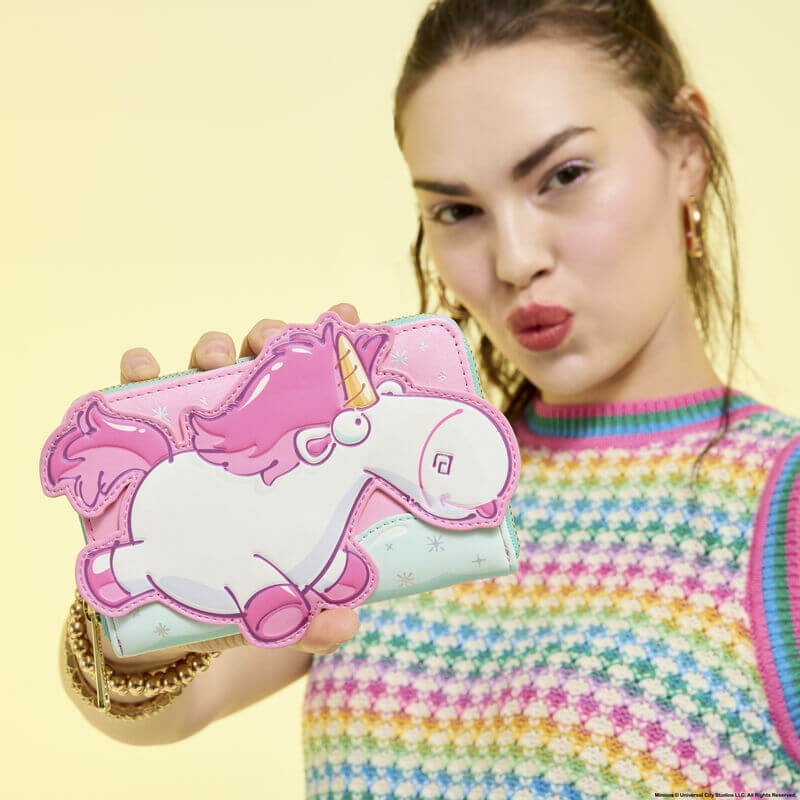 Model holding Loungefly Minions Fluffy Unicorn wallet; oversized unicorn appliqué pops against pastel backdrop – Loungefly bag