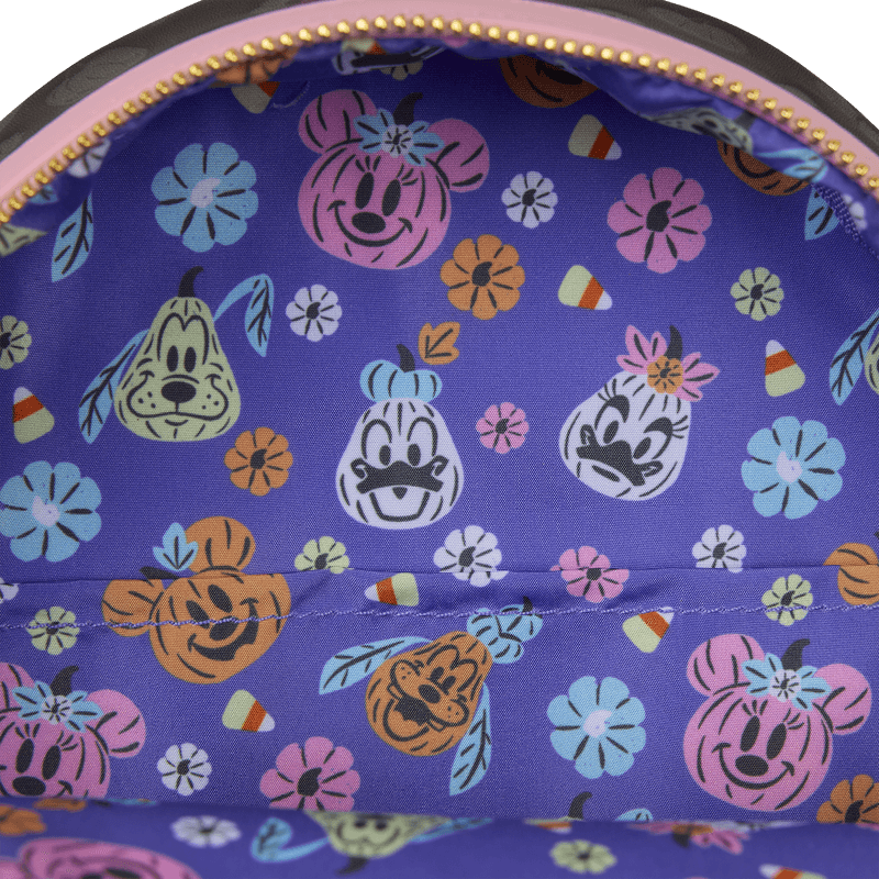 Close-up of purple lining with pumpkin-style Disney character faces and candy print inside the Loungefly Minnie Mouse backpack