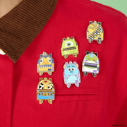 Loungefly Pixar miniature backpack enamel pins displayed on a red jacket featuring Toy Story, Monsters Inc and Up characters