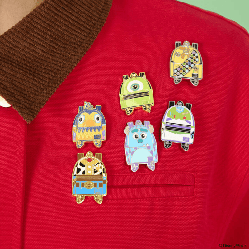 Loungefly Pixar miniature backpack enamel pins displayed on a red jacket featuring Toy Story, Monsters Inc and Up characters