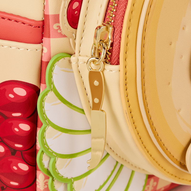 Gold cheese knife zip pull detail on the Loungefly Ratatouille Remy Cheese Wheel Mini Backpack