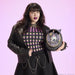 Model holding Loungefly Sanrio Kuromi Cameo mini backpack with pearl handle, studio shot.
