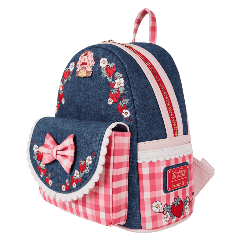 Angled view of Loungefly Strawberry Shortcake faux denim mini backpack with gingham pockets and front flap