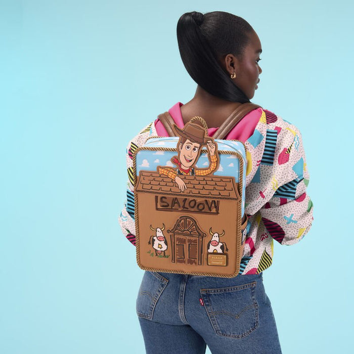 Model wearing the Loungefly Toy Story Woody Saloon Mini Backpack against a blue backdrop