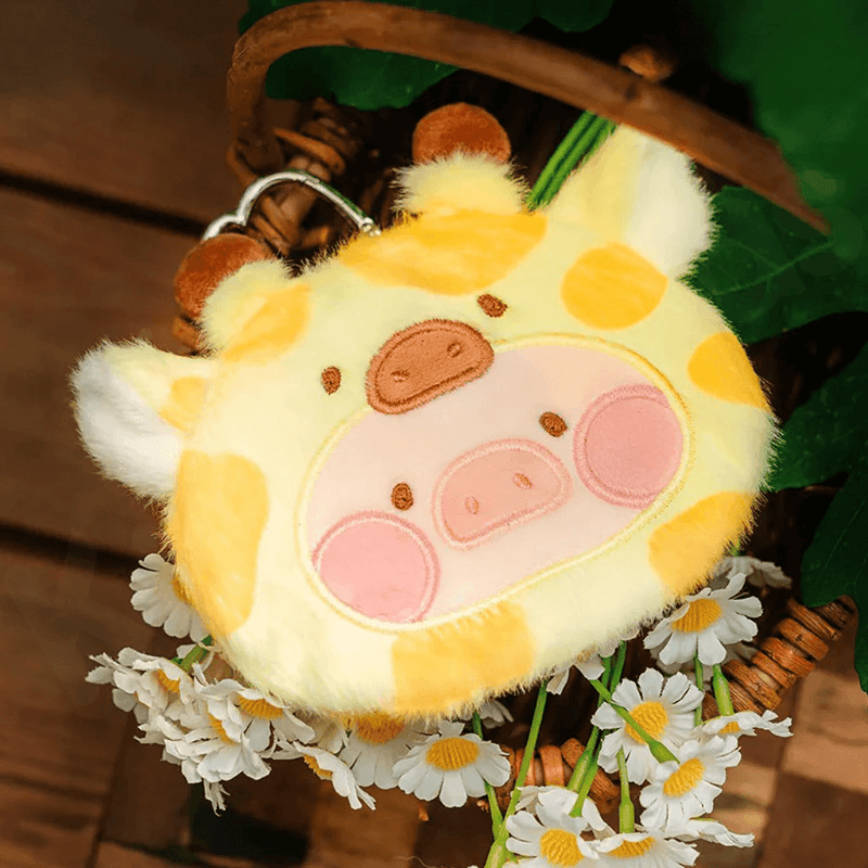 Giraffe Lu plush pouch with yellow spots and little ossicones, pictured beside daisies.
