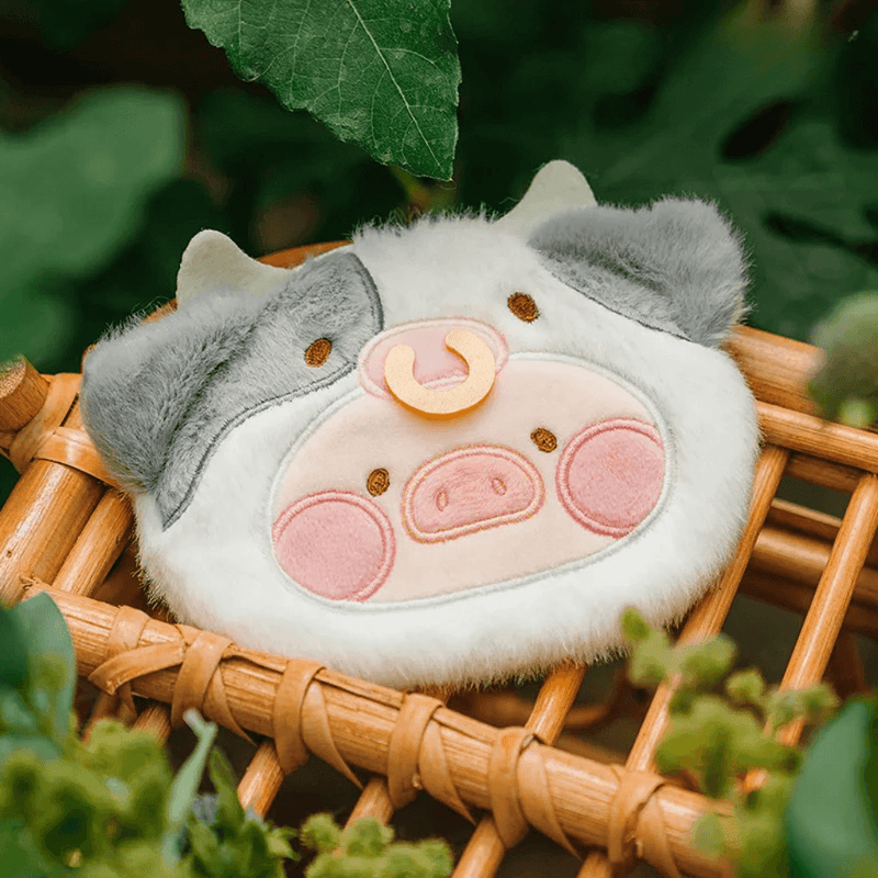 Close-up of Moo Lu plush pouch, Lulu the Piggy in a cow hood, showing embroidery and soft fur.
