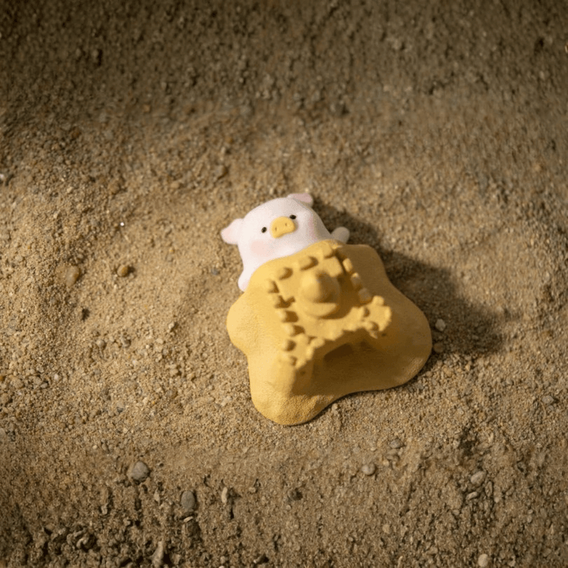 LuLu the Piggy Beach Party Blind Box Series Sandcastle figure peeking out from behind a sandcastle on the beach