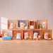 Lulu the Piggy blind box display showing nine mini figures in diorama tins, including bath, breakfast and drawing scenes.