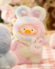 Lulu the Piggy Joyful Time blind box plush in pastel-rainbow bunny outfit with matching bunny purse on picnic cloth.
