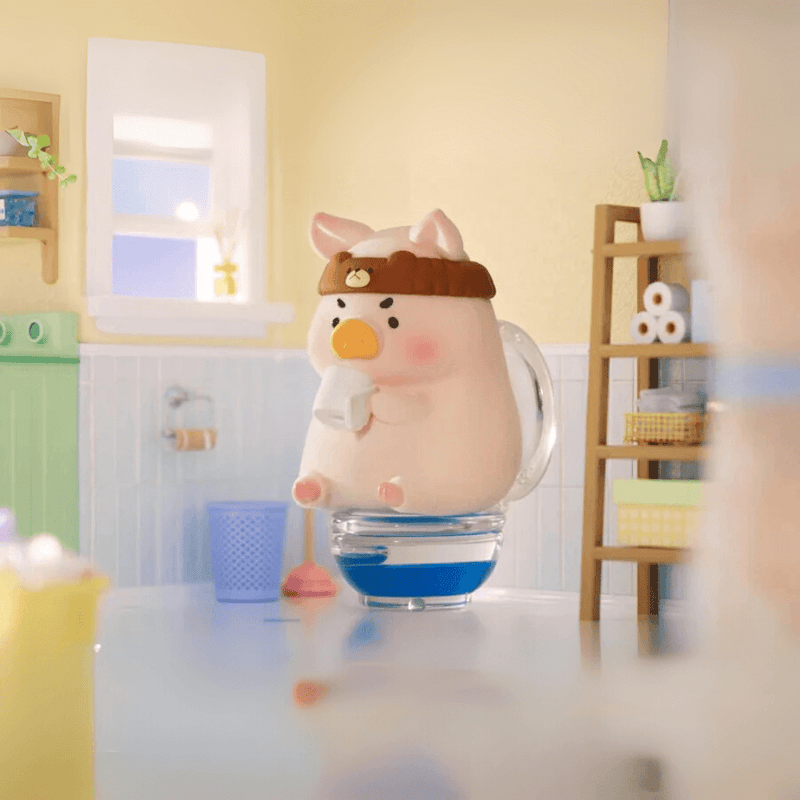 Lulu the Piggy Home Life blind box “Tea Break” figure—pig sipping from mug while seated on a clear toilet tank in light-filled bathroom.









