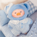 Lulu the Piggy Sleep Well plush keychain in pale blue sleep outfit resting on bedding
