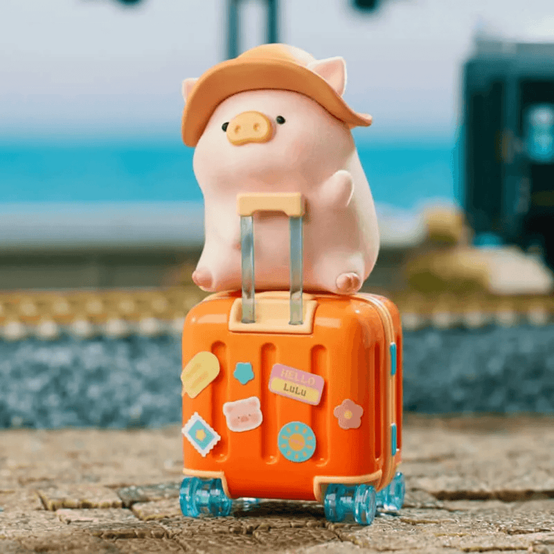 LuLu the Piggy's Travel Series Blind Box pig figure sitting on an orange suitcase with travel stickers