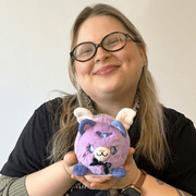 Person holding Squishable Alter Egos Magical Kitty Plush in lavender with wings and purple bow