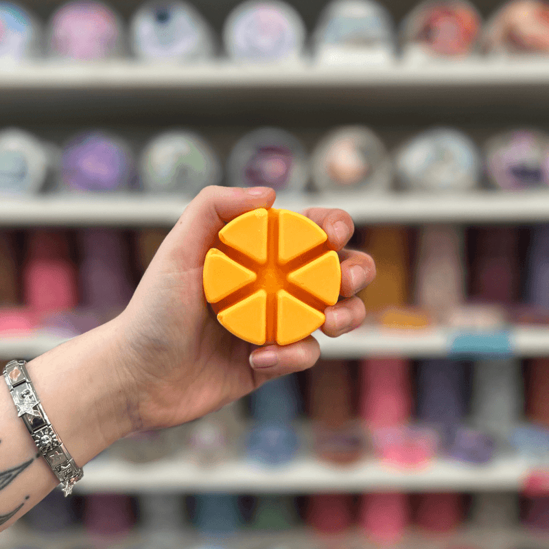 Mango Peach Salsa wax melt segments held in hand with colourful wax melt display in the background