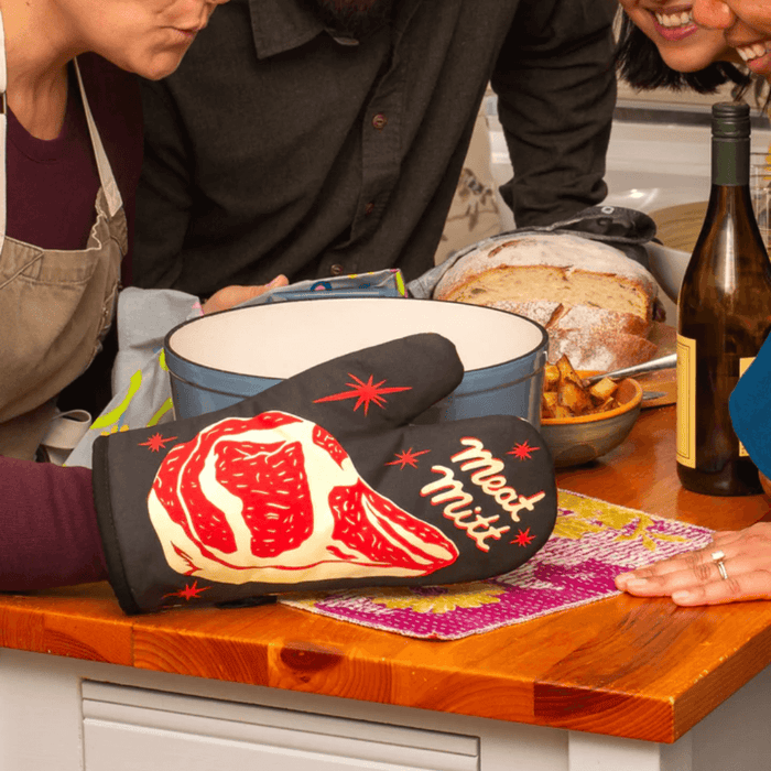 Meat Mitt oven mitt on a kitchen counter beside a large pot during cooking.
