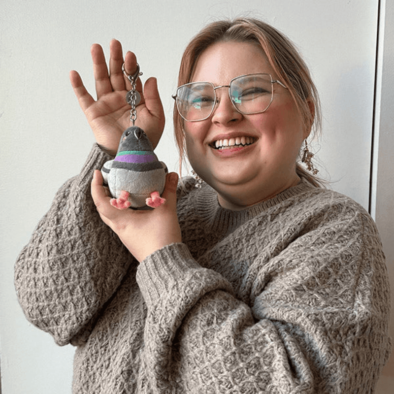 Micro Squishable Pigeon plush keychain being held for size comparison