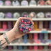 Midnight Pomegranate wax melt pot held in hand with colourful wax melt display in the background
