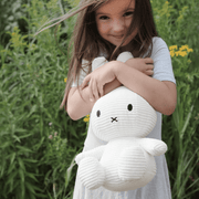 Child holding Miffy Corduroy Eco White 33cm plush toy outdoors