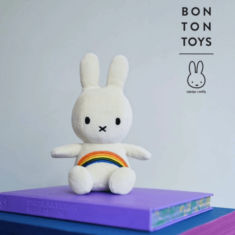 Miffy Rainbow white corduroy plush toy by Bon Ton Toys displayed on books