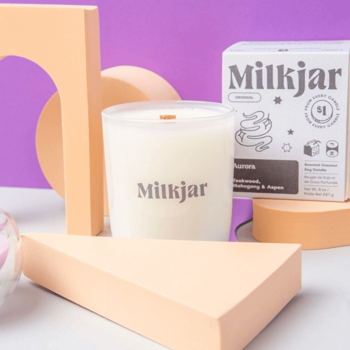 Styled close-up of Milkjar Aurora frosted glass candle with Milkjar branding and box.