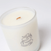 Close-up of Milkjar Aurora candle in frosted glass with wooden wick and Aurora logo.