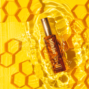 Milkjar Before Sunrise perfume roller bottle in water splash on yellow honeycomb backdrop