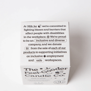 Back of The Feel-Good Candle Co box with inclusive workplace and $1 donation message.