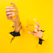 Hands squeezing an orange next to a Milkjar Citrus candle against a bright yellow background.
