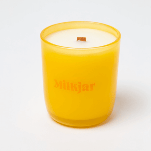 Milkjar Citrus essential oil candle in yellow glass with crackling wooden wick on white background.