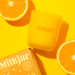 Milkjar Citrus candle in yellow glass with oranges and box on a bright yellow background.