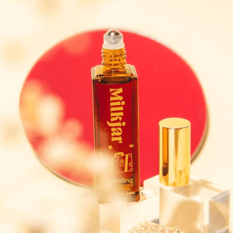 Open Milkjar Darjeeling perfume roller showing rollerball with gold cap beside bottle on clear blocks