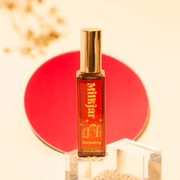 Styled Milkjar Darjeeling perfume roller on clear blocks with red backdrop and sandy texture