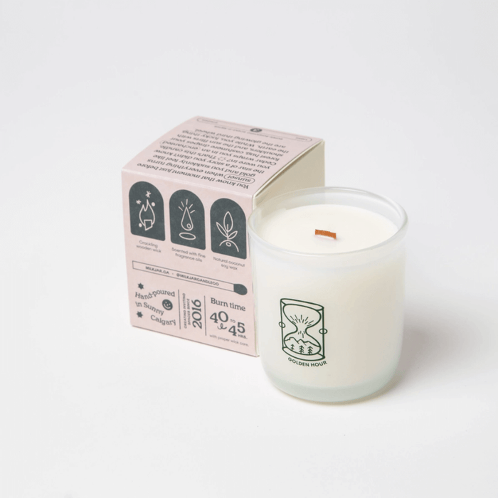 Milkjar Golden Hour coconut soy candle next to the box showing burn time and product icons.