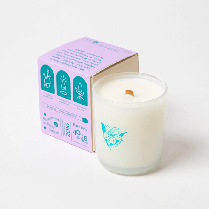 Milkjar Hawaii candle beside the box showing icons for wooden wick, fragrance oils and coconut soy wax.