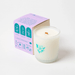 Milkjar Hawaii candle beside the box showing icons for wooden wick, fragrance oils and coconut soy wax.