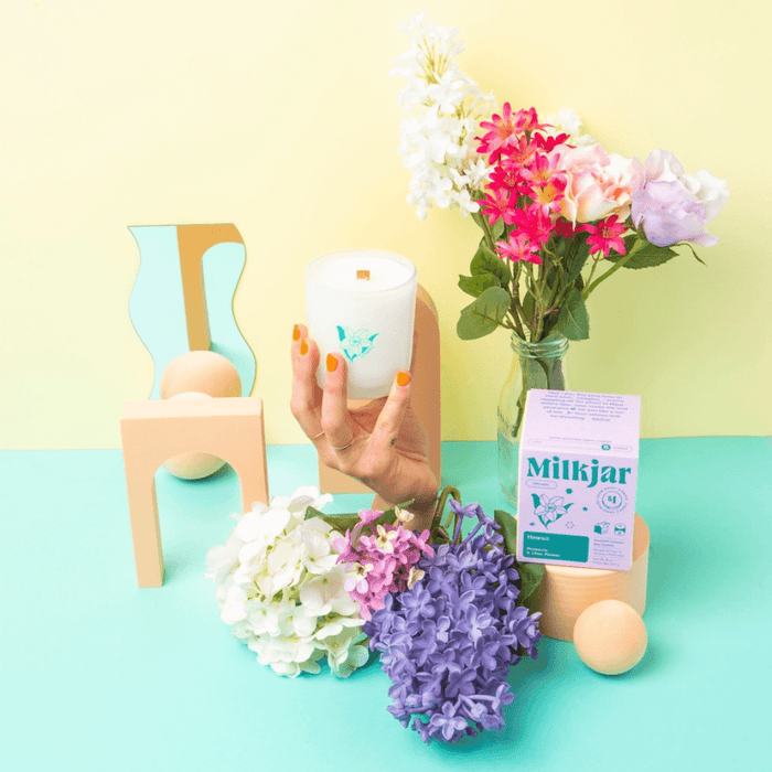 Milkjar Hawaii candle styled with colourful flowers, pastel props and a hand holding the frosted glass candle.