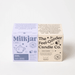 Milkjar Hygge candle box beside The Feel-Gooder Candle Co. packaging on a white background.