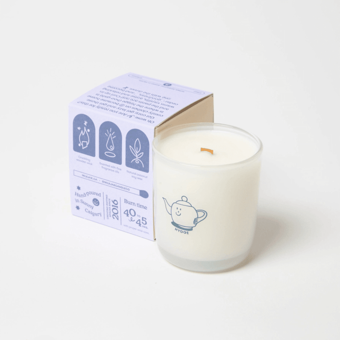 Milkjar Hygge candle with box angled behind, showing wooden wick, fragrance oil and coconut soy wax icons.