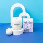 Milkjar Hygge coconut soy candle and box styled on a bright blue set with minimalist arch props and a wooden wick.
