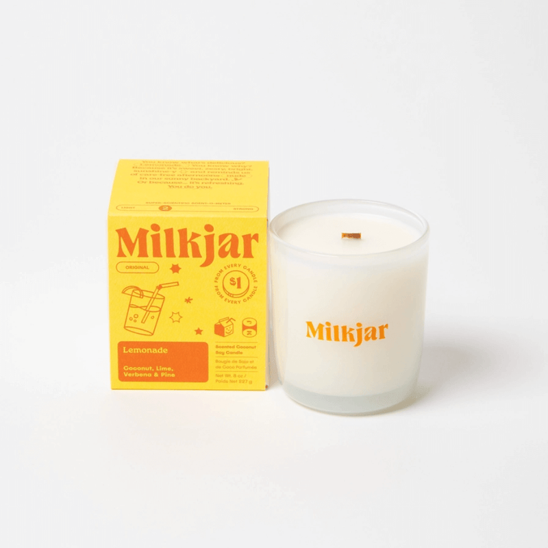 Close-up of Milkjar Lemonade candle with Milkjar branding on a bright yellow set with the candle box in the background.