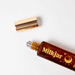Milkjar Moonrise perfume roller lying open with cap beside bottle on a white background