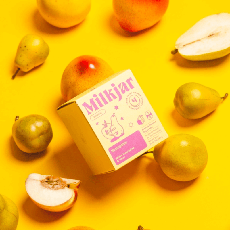 Sunnyside candle box styled with pears and nectarines on a bright yellow background.