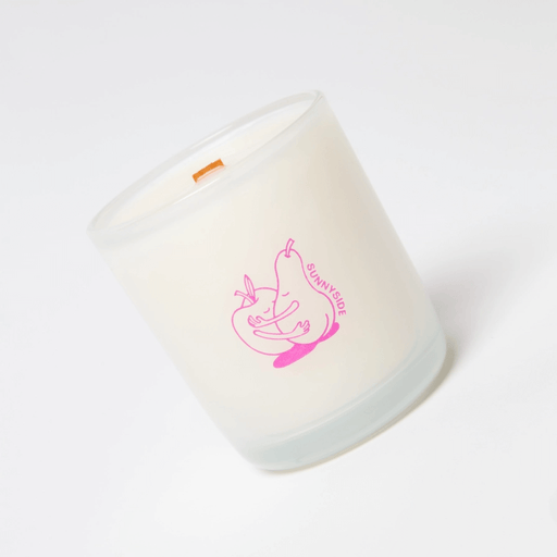Close-up angled view of Milkjar Sunnyside candle in frosted glass with wooden wick and pink pear and nectarine icon.