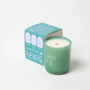 Milkjar Woodland green glass candle with box angled behind, showing wooden wick, essential oils and coconut soy wax icons.