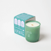 Milkjar Woodland green glass candle with box angled behind, showing wooden wick, essential oils and coconut soy wax icons.