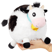 Front view of Squishable Mini Cow plush toy with pink snout and yellow jingle bell collar