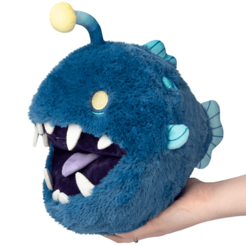 Mini Squishable Anglerfish plush with deep-blue fur, white teeth, turquoise fins and yellow lure