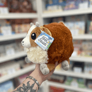 Mini Squishable Baby Goat plush toy held in hand, angled view showing the rounded body, soft brown plush fur, cream face and fluffy chest detail
